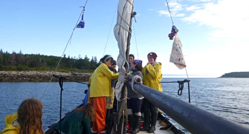 A group of students work with the sail of a boat.